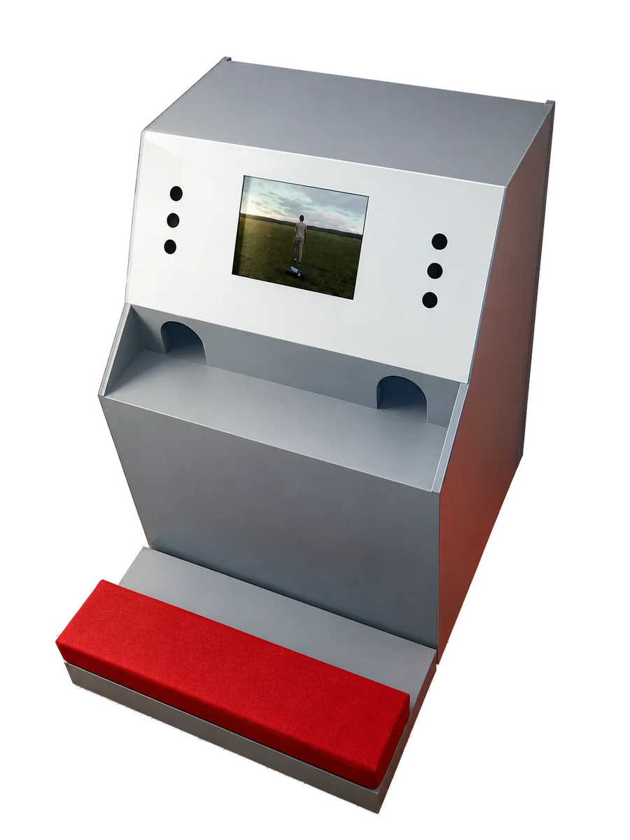 Die 2003 gebaute Antwortmaschine: geneigter Monitor, zwei Handöffnungen, rotes Kniepolster